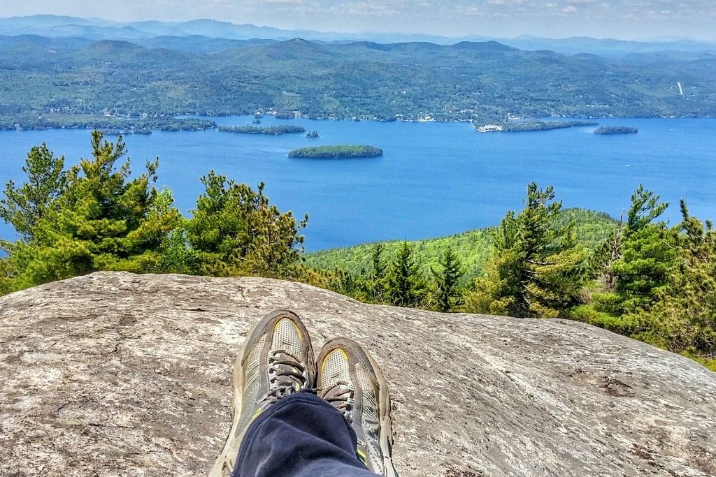 One of the best things to do in Lake George NY is climb to the top of Buck Mountain and get this aerial view of Lake George with the green hills in the background.