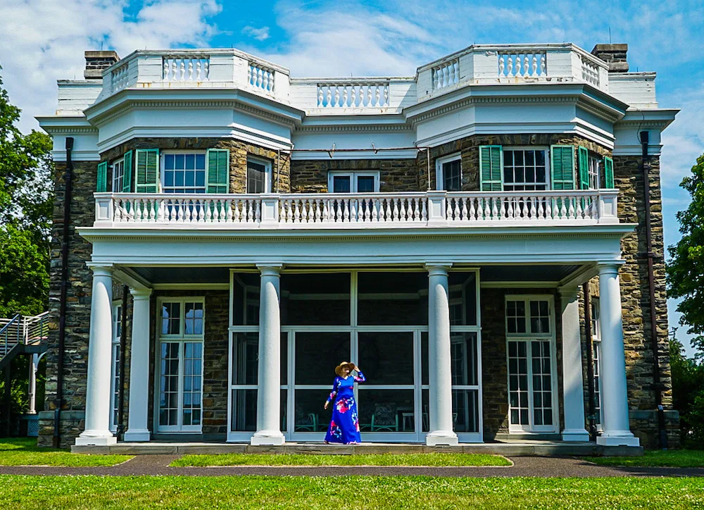 Girl in a blue dress standing in front of the FDR home in Hyde Park, NY. Visiting this is one of the iconic things to do in Poughkeepsie NY