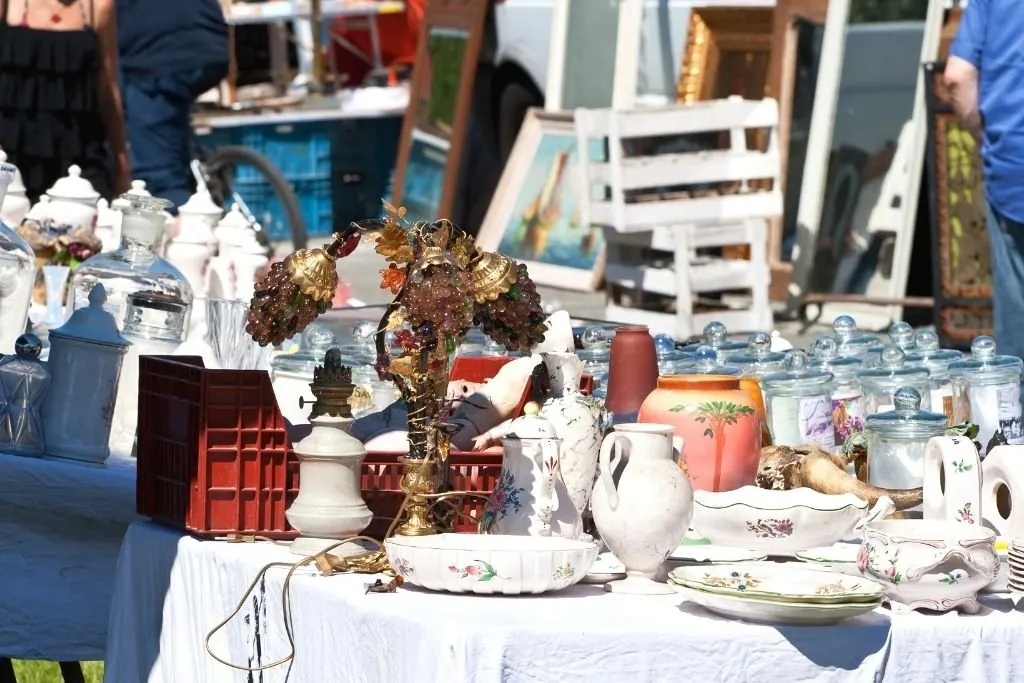 A collection of antiques including glass bottles, lamps and ceramics stacked on a table in one of the best places to shop in NYC on a budget