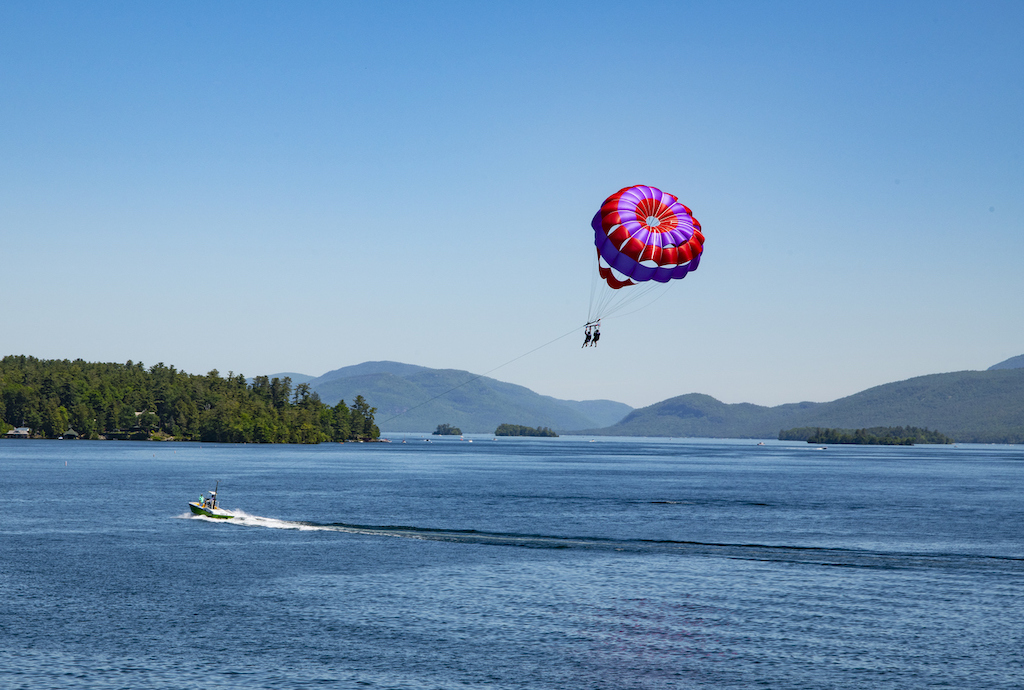 View of Lake George and mountains with two parasailing persons in the foreground.