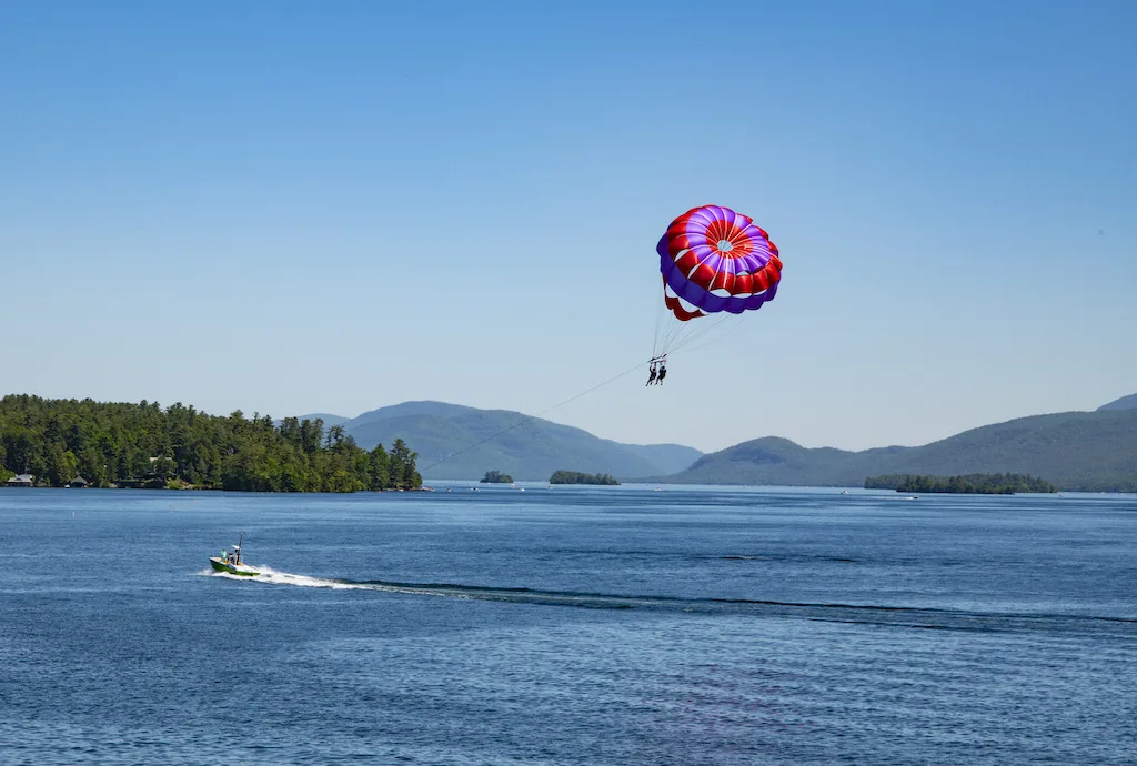 View of Lake George and mountains with two parasailing persons in the foreground.