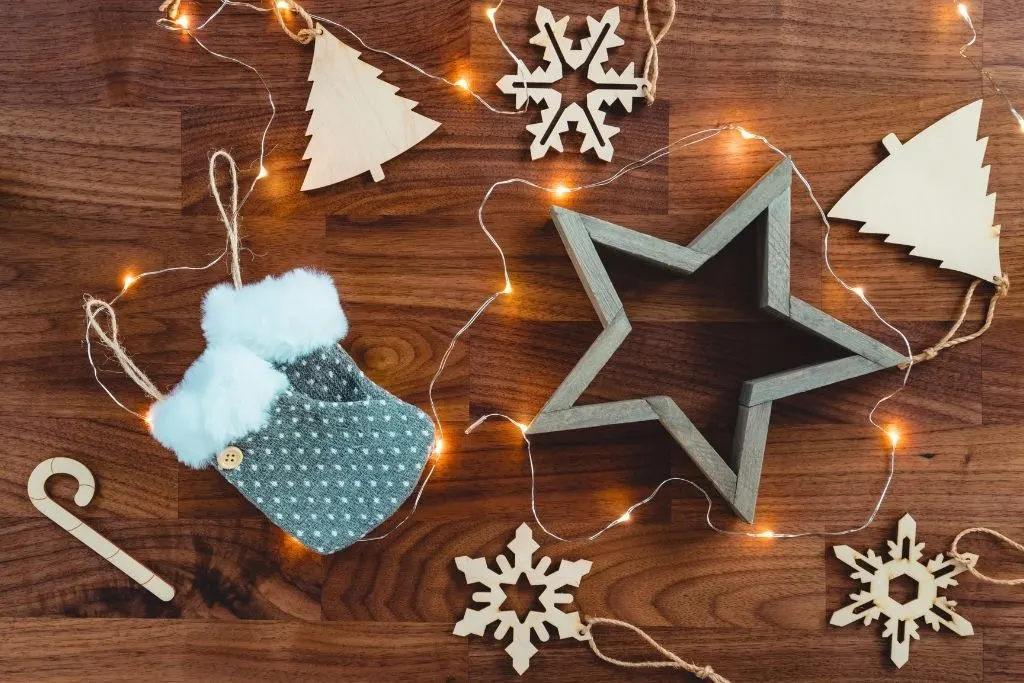 Homemade Christmas ornaments on a wooden table surrounded by holiday lights. 