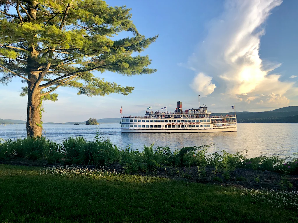 A steamboat sailing across Lake George at sunset