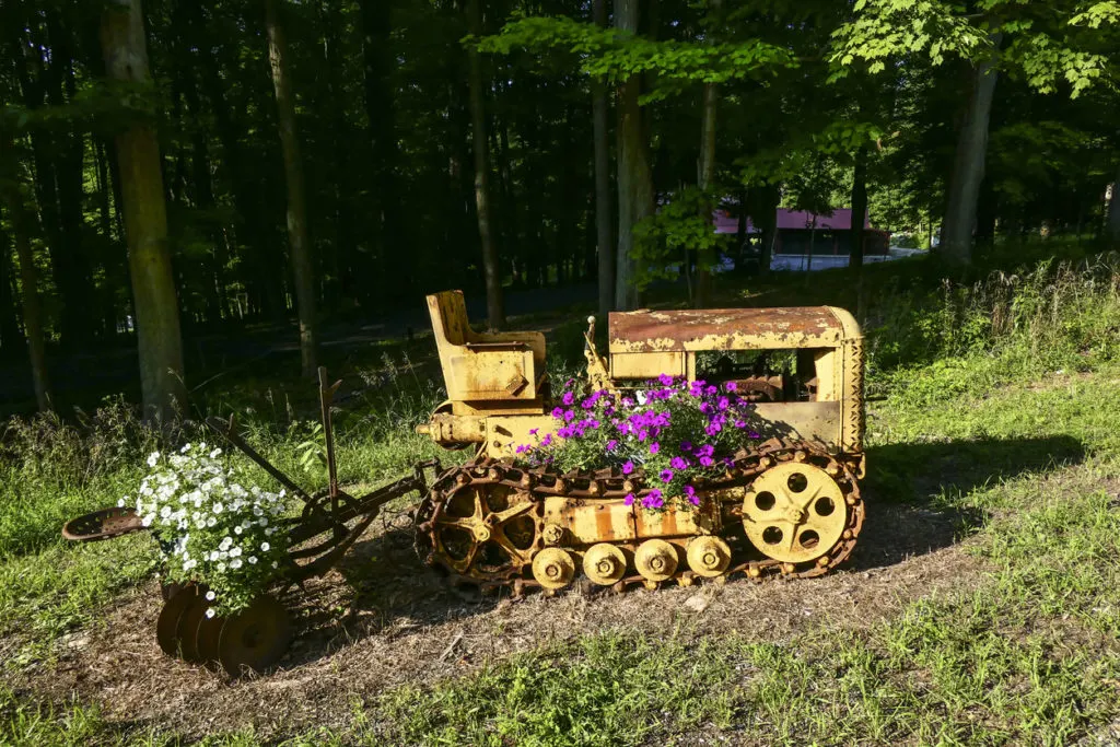 An old Caterpillar tractor repurposed into a flower pot on the side of the road. (Amenia, Dutchess County, New York, USA 