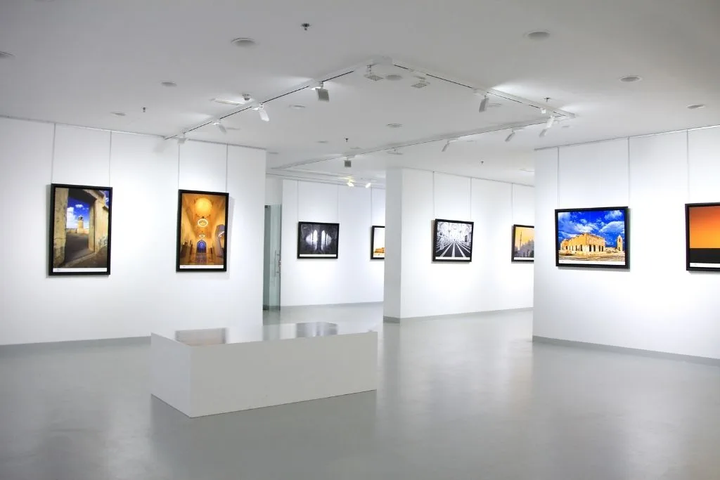 Modern art gallery with sleek, white walls and paintings for sale. 