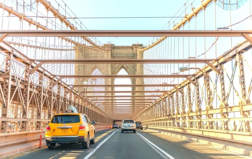 Cars and taxis driving across the Brooklyn Bridge in New York City. One of the many pros and cons of living in New York City is the traffic. 