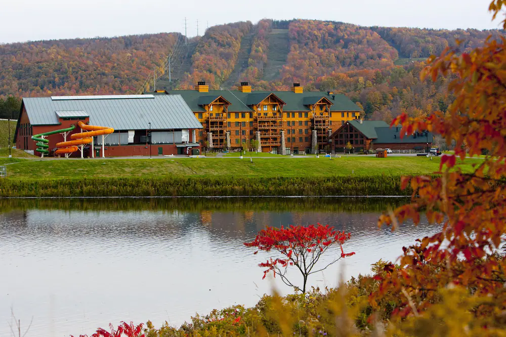 Panoramic view of Hope Lake Lodge with a lake in front and surrounded by fall folliage. 