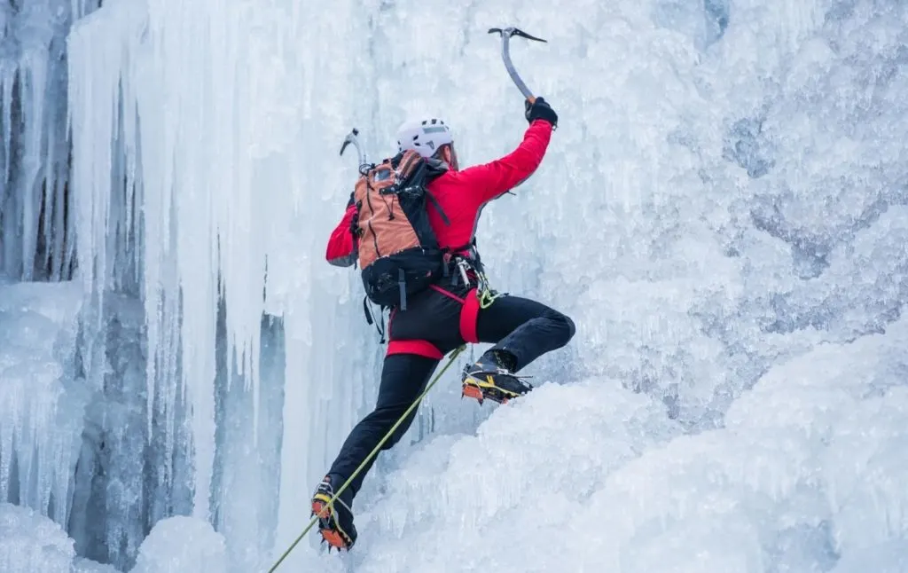 Climber in a red jacket going up an ice wall in Lake Placid. 