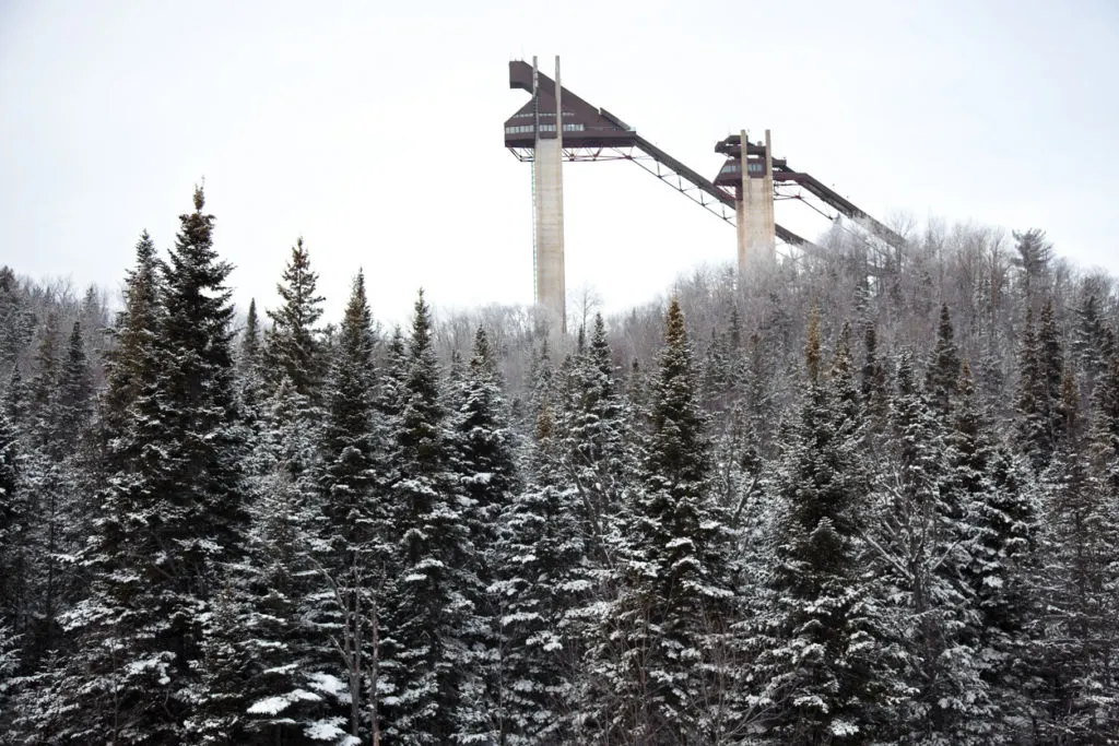 Ski jumps in winter and pine trees covered in snow in Lake Placid. It's one of the best Christmas towns in New York. 