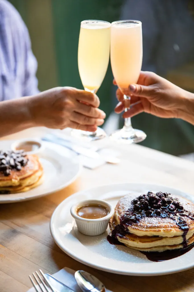 Mimosas and blueberry pancakes at Clinton Street Baking Company in NYC. Brunch is one of the pros on this list of pros and cons of living in New York City.
