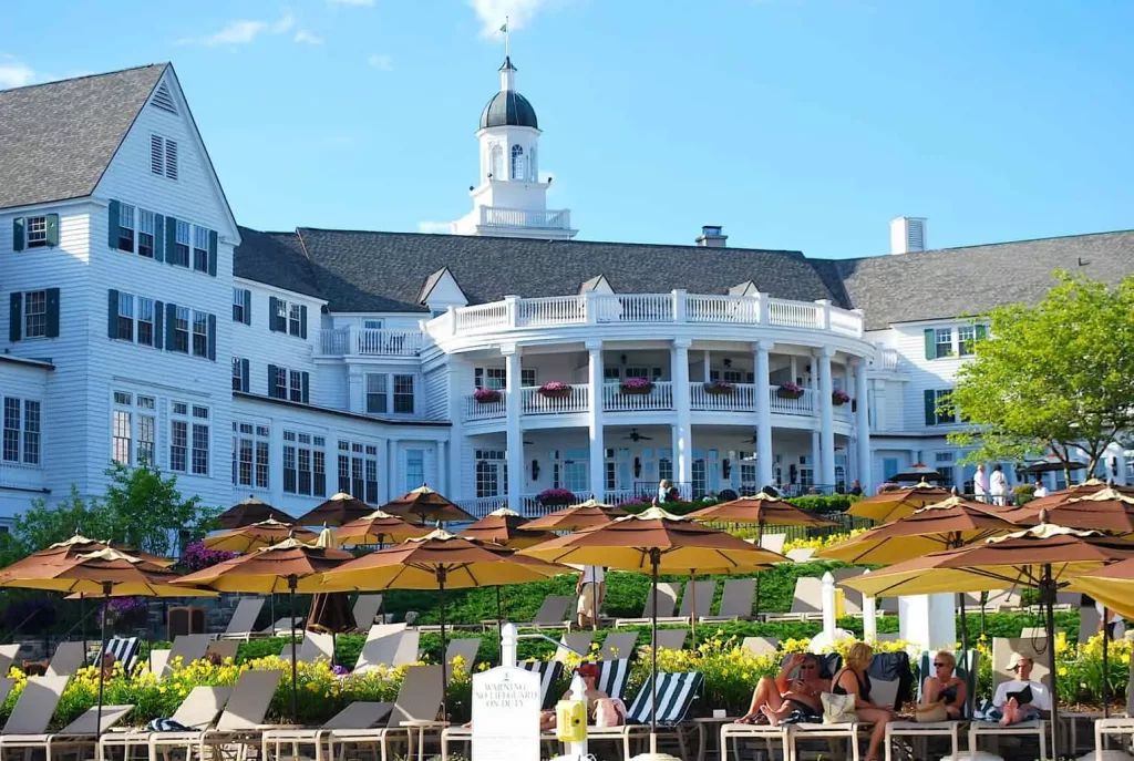 The impressive exterior fo the Sagamore Resort and guests sitting by the pool. 