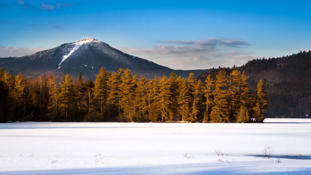 Whiteface mountain peak covered in snow as seen from the frozen Paradox Bay in Lake Placid, Upstate New York