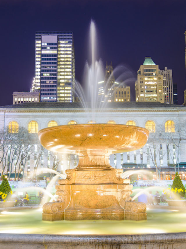 The fountain at Bryant Park in the evening with the New York library in the background.