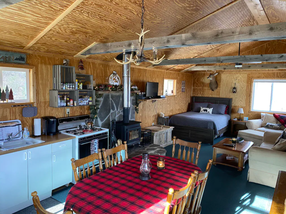 The rustic interior of the Big Medicine Ranch Cabin with a wood-burning stove and spacious bed. 