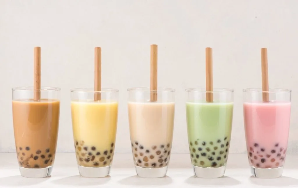 Five different bubble teas on a table in different colors. 