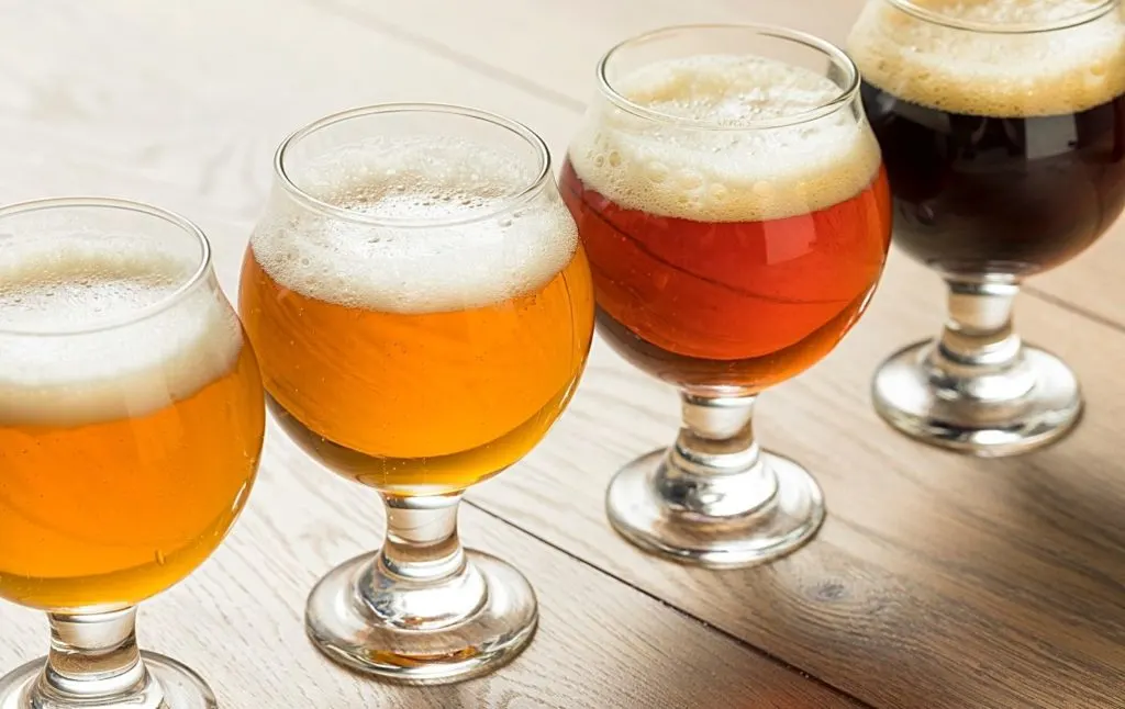 Flight of different colored beers on a table. 