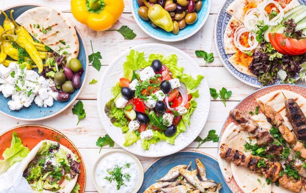 Table full of traditional Greek food which includes fish, wraps, salad, olives, cheese and more. Definitely one of the tastiest things to do in Sleepy Hollow NY.