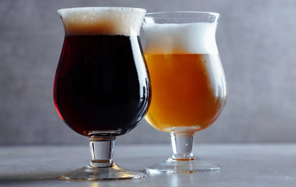 View of two beer glasses. One with light beer and one with dark beer.