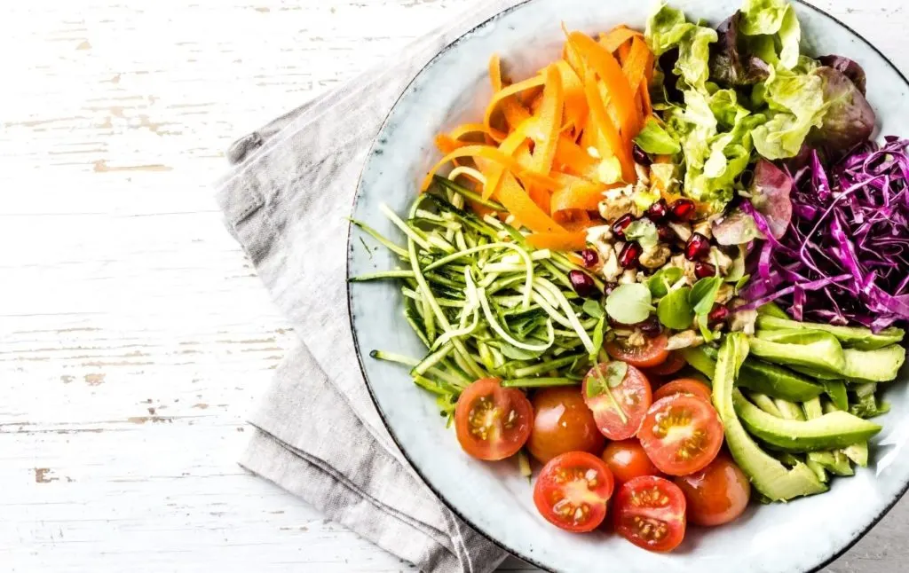 Salad in a bowl on a white, wooden table. 