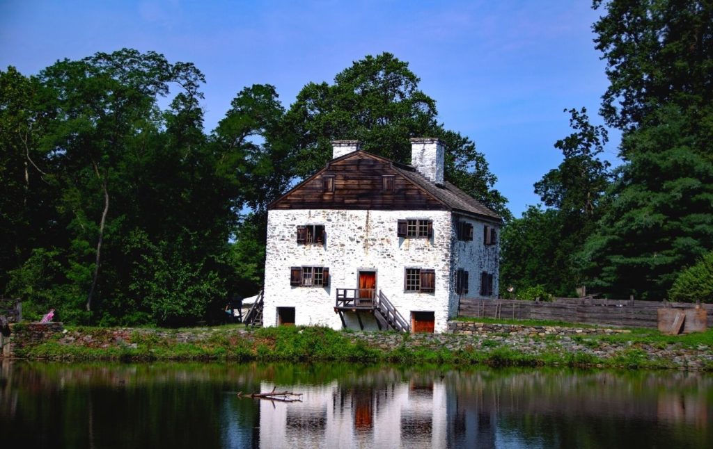 Vacant, historic, white brick farmhouse on the water in Sleepy Hollow New York with a red door. Visiting this is one of the iconic things to do in Sleepy Hollow.