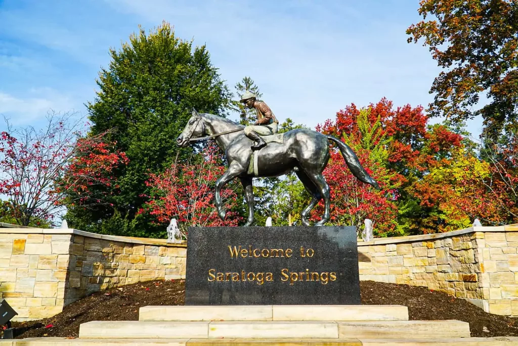 Welcome to Saratoga Springs sign with a jockey and horse on top at Congress Park.