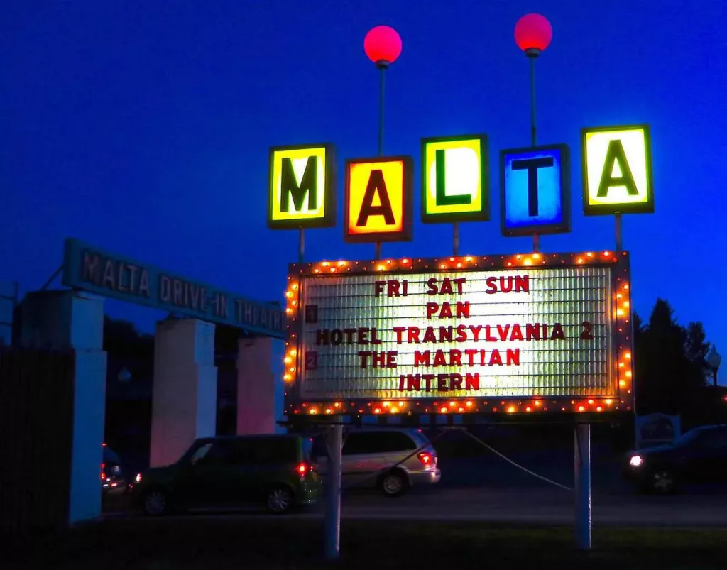 Neon sign in front of the Malta drive which shows the current playing movies In theater in Saratoga Springs. 