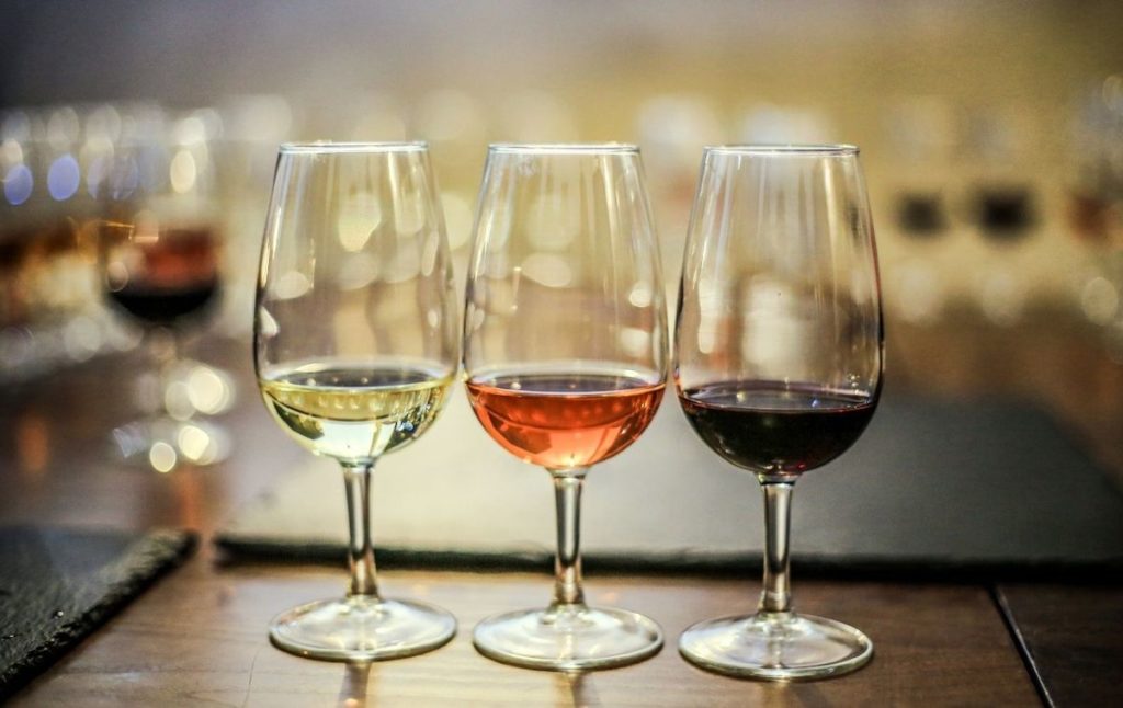 Bordeaux glasses that are full of samples of red, white, and rose wine. 