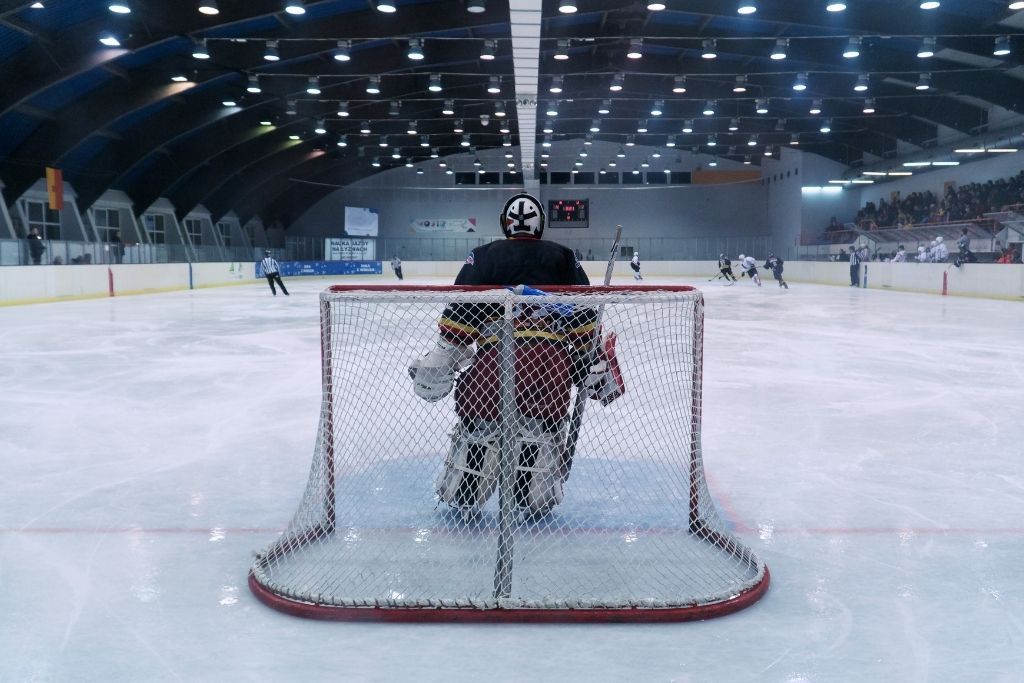 Goalie standing in the goal on an ice rink during a hockey match. This is one of the best things to do in Winter in Lake George