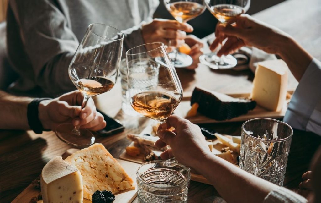 Friends toasting their wine glasses with cheese boards in the background at one of the best Seneca Lake wineries. 