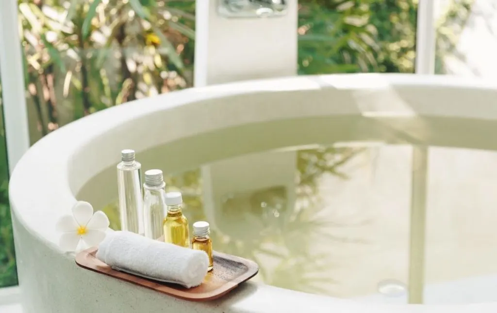 Modern white tub with bath products and a rolled-up white towel at one of the cool hot springs in NY