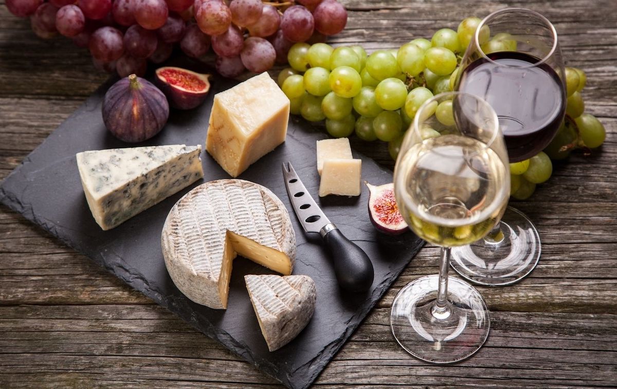 Cheese board with a glass of red and white wine on the side.