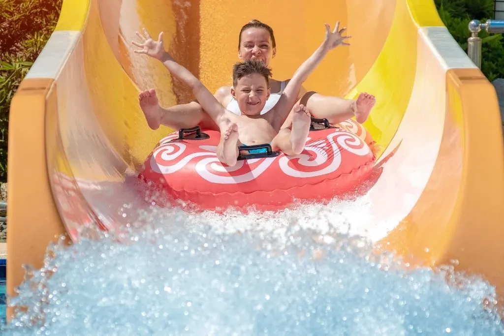 Mother and son going down a waterslide in an intertube. 