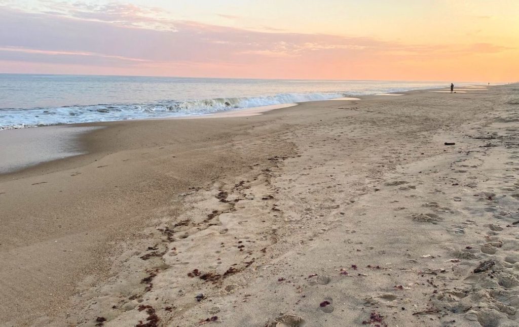 Person walking along Kirk Park Beach at sunset in Montauk, one of the top Montauk beaches. 