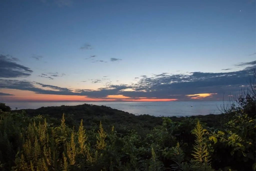 View of the sun setting on the ocean from Montauk Point State Park, one of the best hikes on Long Island. 