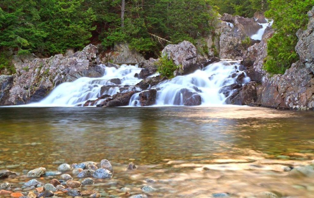 Pool beneath split rock falls in the Adirondacks with its clear water and spectacular views is one of the best swimming holes in NY., 