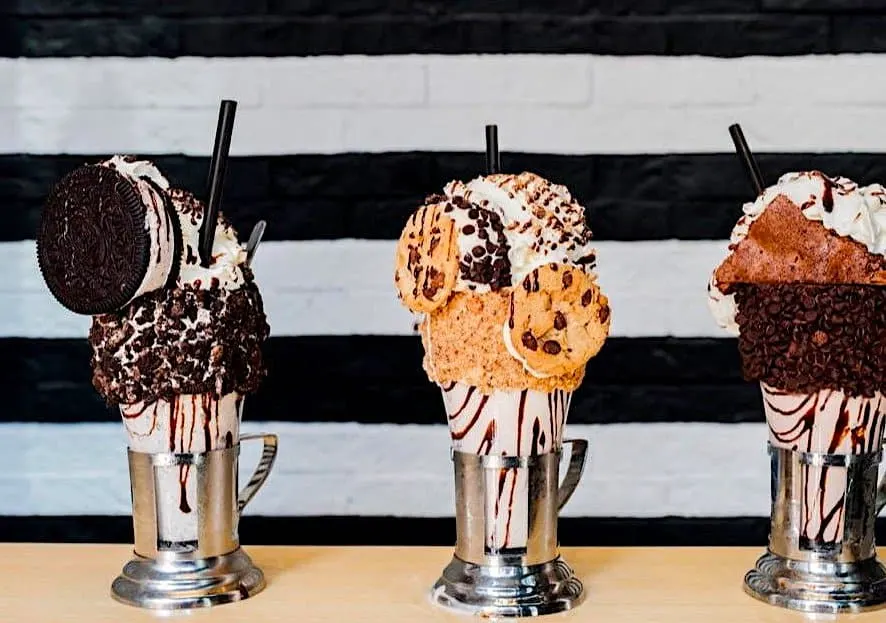 Decadent milkshakes topped with cookies whipped cream and loads of chocolate sprinkles at Black Tap, one of the quirky restaurants in NYC. 