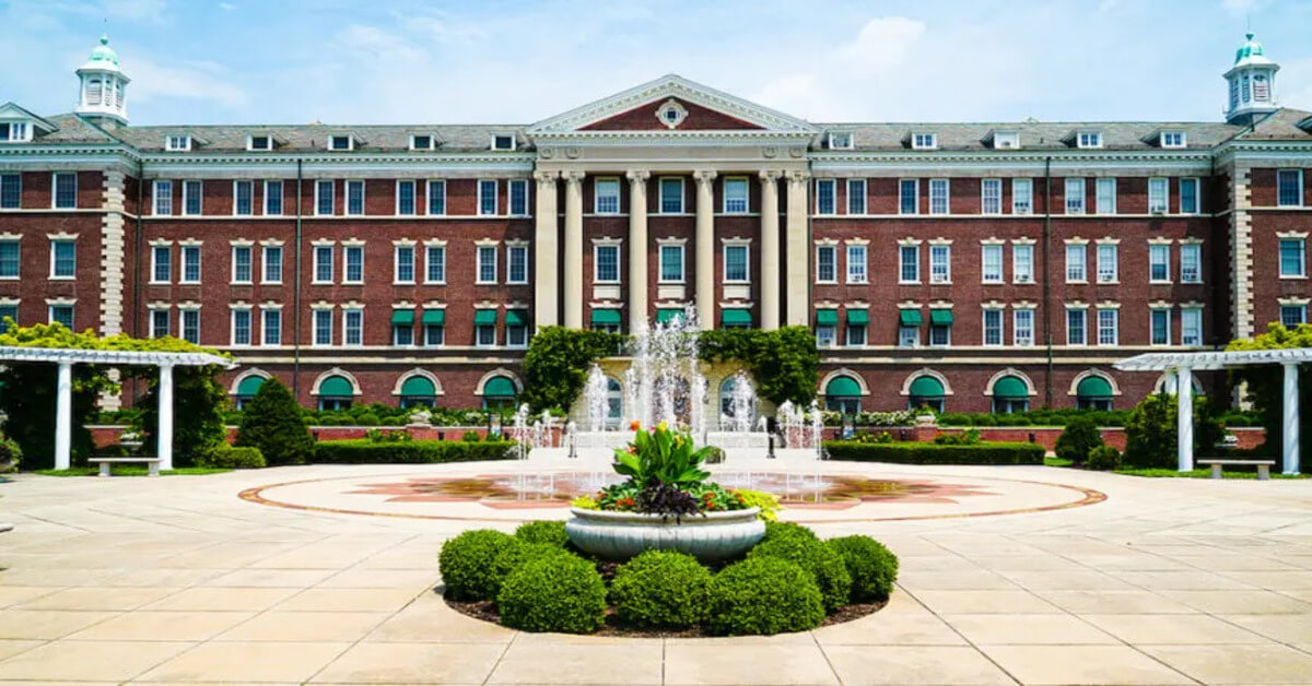 Outside view of the brown and white building of the Culinary Institute of America with its fountains and gardens in the foreground. Visiting this place is one of the best things to do in Poughkeepsie NY for foodies.