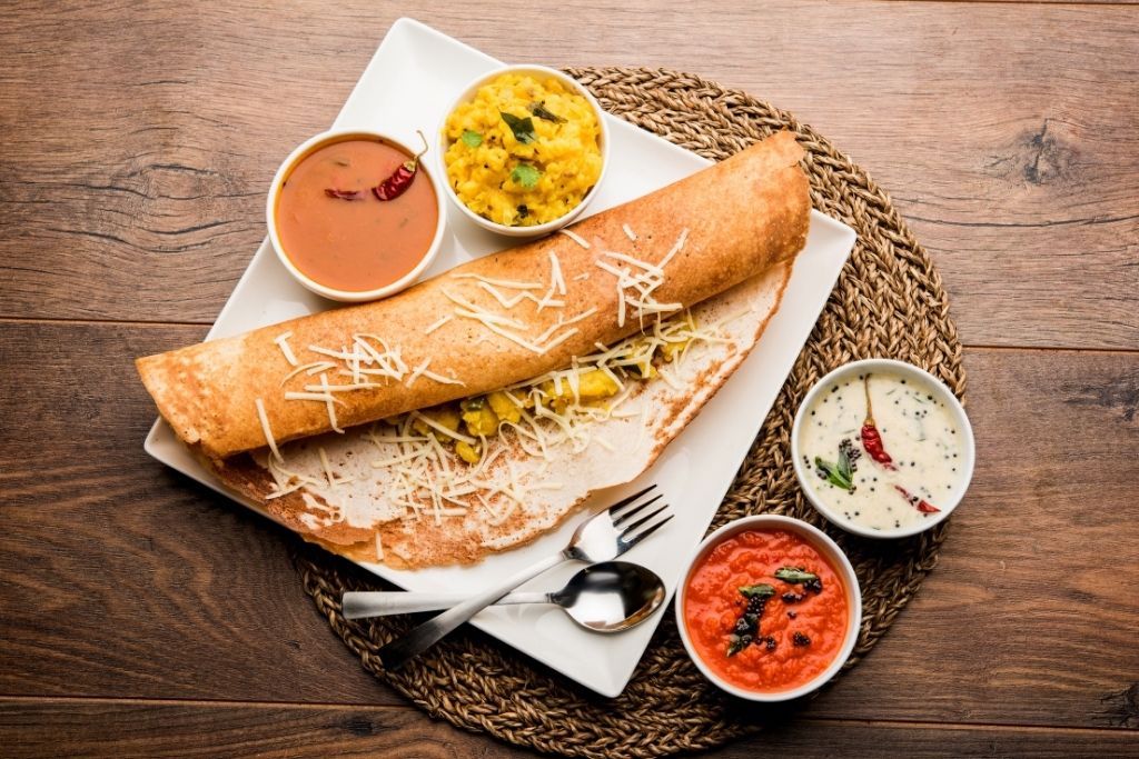 Indian dosa rolled with potato filling and three dips on a table at one of the fun restaurants in NYC.