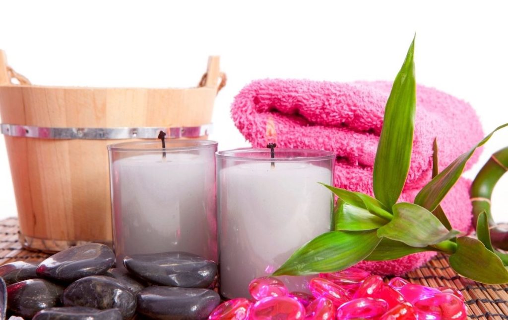 Pink towel, candles, and a wooden bucket from a yoga spa. 