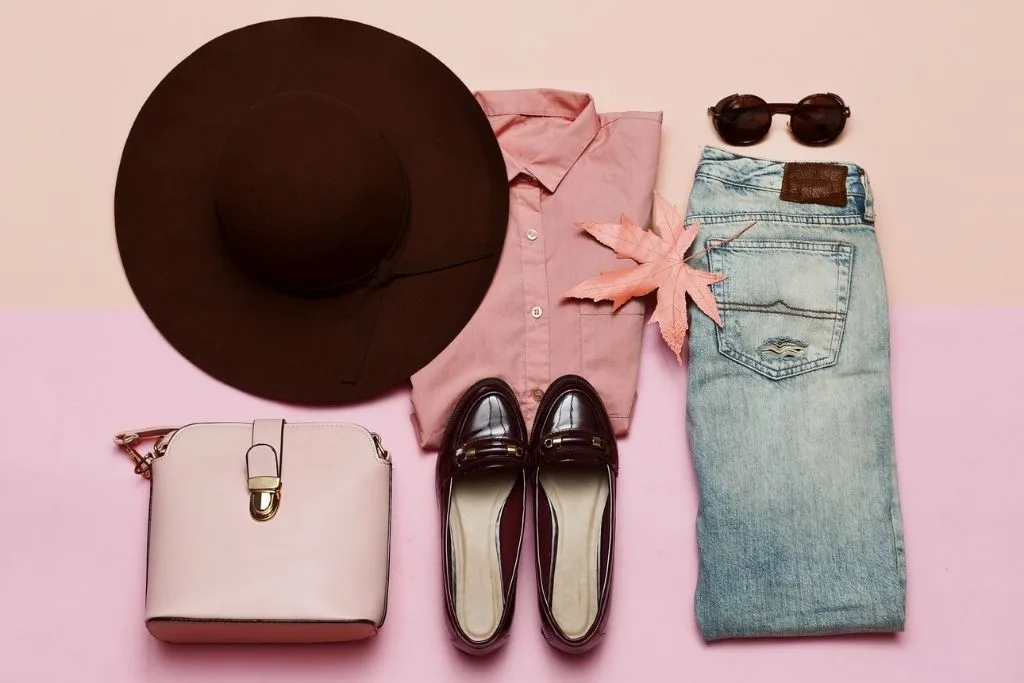 Well-laid out clothes including denims, a wide brim cat, brown walking shoes, a shirt and a bag from one of the best places to shop in NYC on a budget. 