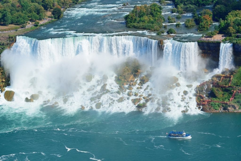 Aerial view of Niagara Falls with a river boat in the forground.