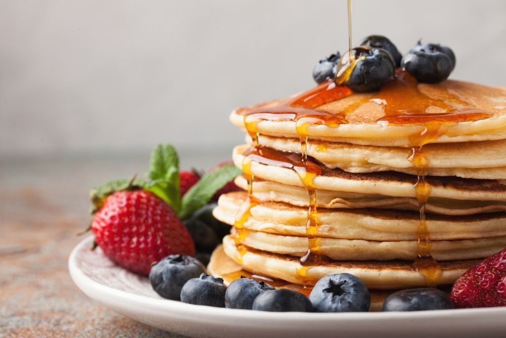 Stack of pancakes with fresh fruit and maple syrup during your one day in Niagara Falls itinerary. 