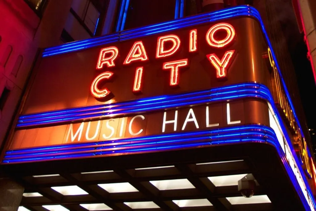 View of the marquis sign in front of radio city music hall and a place that shoudl eb on your New York City bucket list.