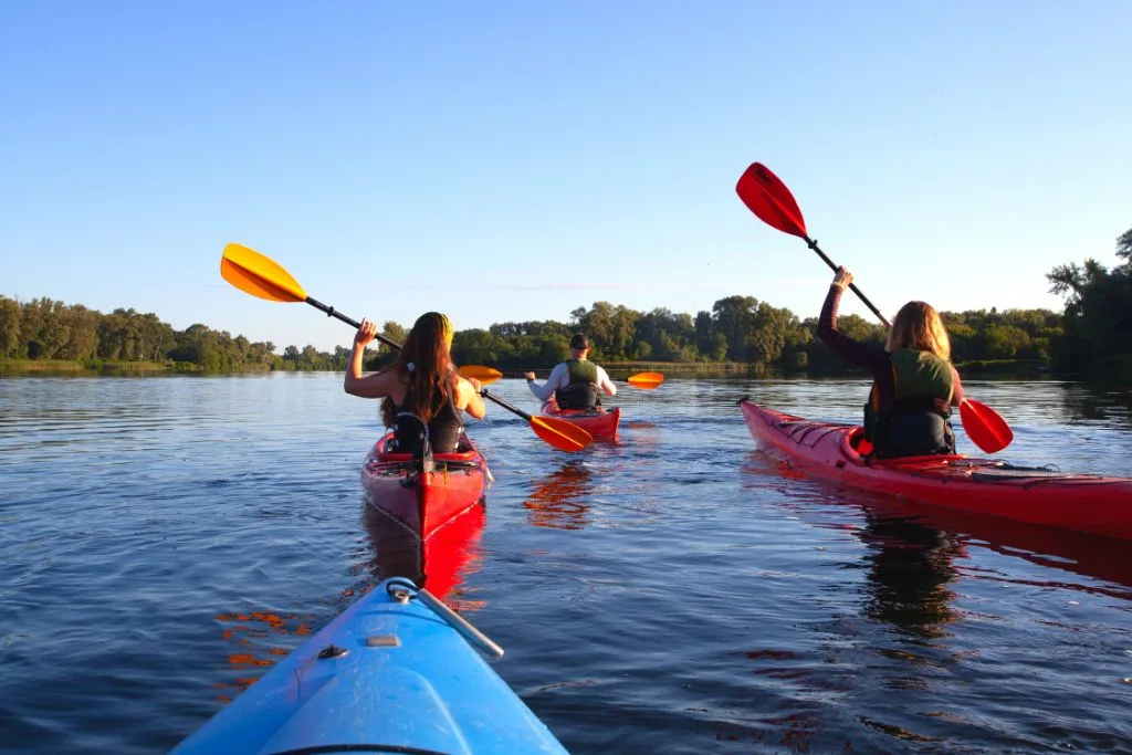 Group of people on the water in their boats with paddles and kyaking, enjoying one of the best things to do in Montauk. 