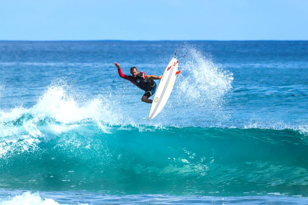 A man hitting the waves and jumping in the air while surfing and enjoying the top things to do in Montauk NY. 