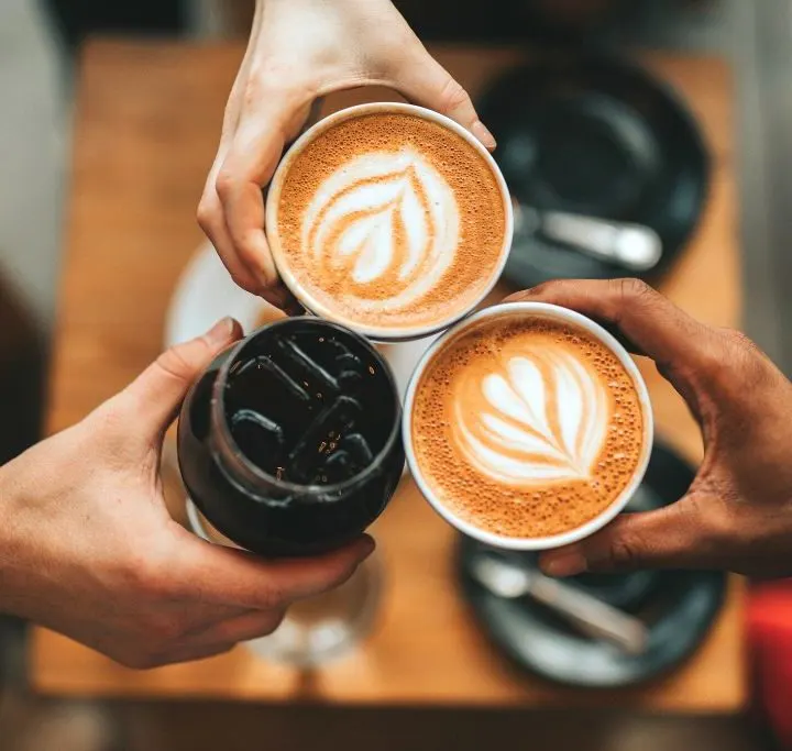 Three people holding their coffee together.