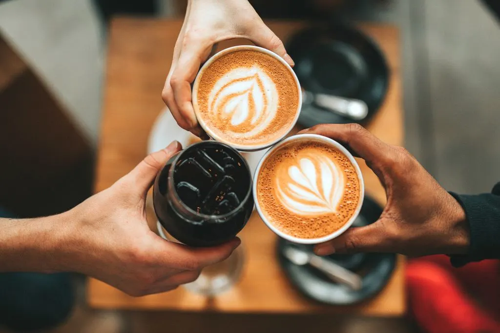 Three people holding their coffee together. 