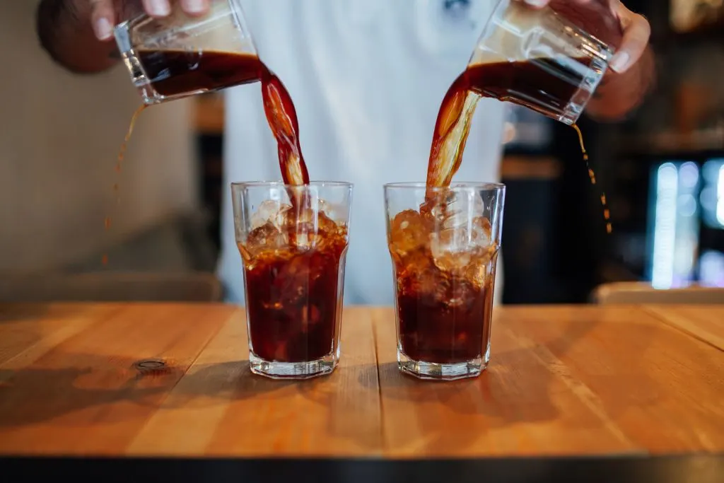 Barista making two cups of cold brew coffee at one of the best coffee shops in Brooklyn. 