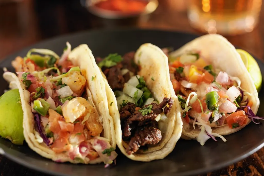 An assortment of three fresh tacos on a plate from one of the fun restaurants in NYC for adults. 