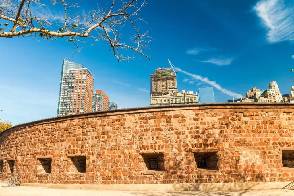 View of Castle Clinton brick facade with skyscrapers in the background in lower Manhattan at one of the top castles in New York. 